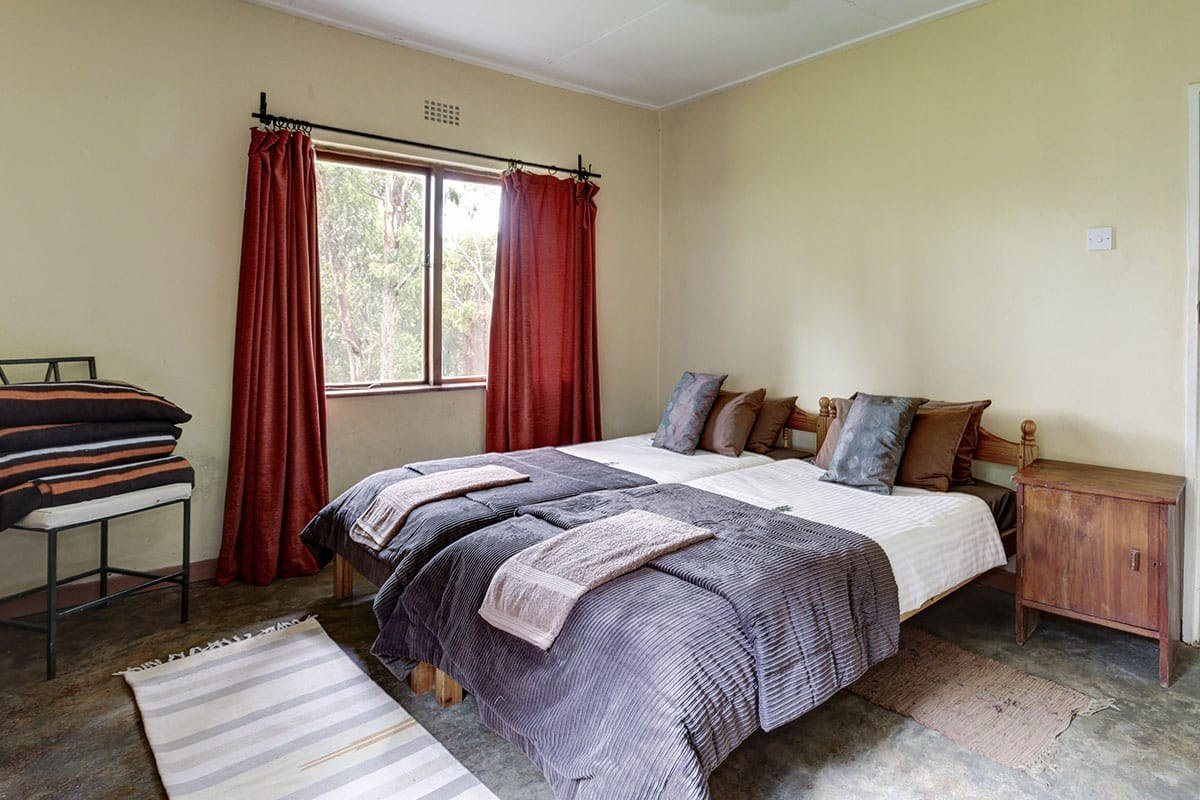 Twin beds with heavy curtains in a guest room at Chelinda Camp
