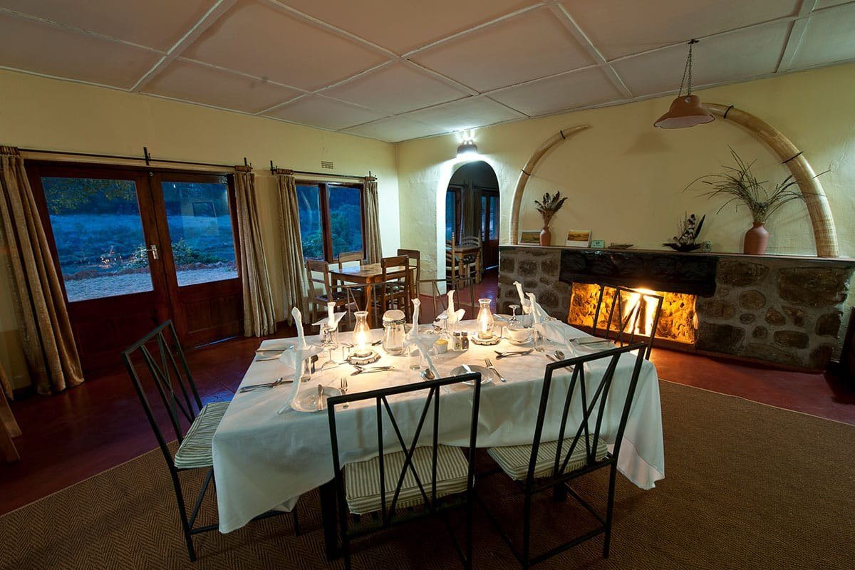 A candlelit dining table beneath mounted tusks at Chelinda Camp