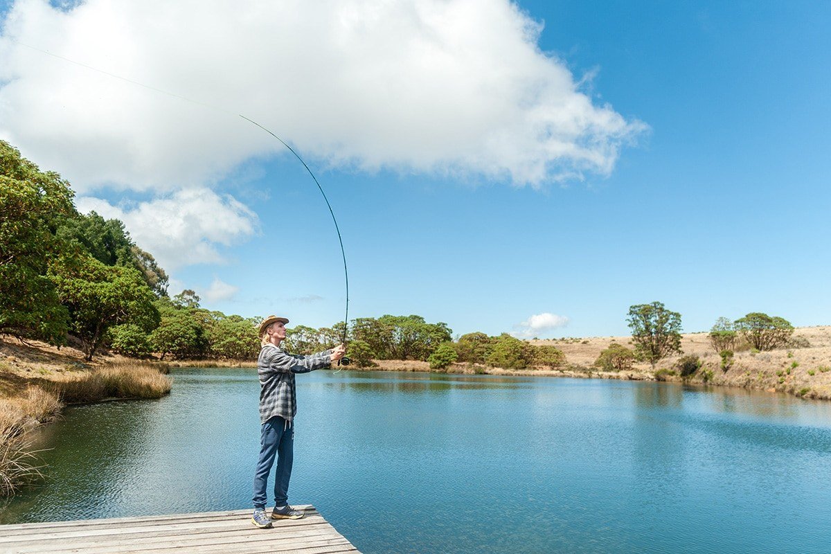 A guest casts a fly fishing line on the dam at Chelinda Camp