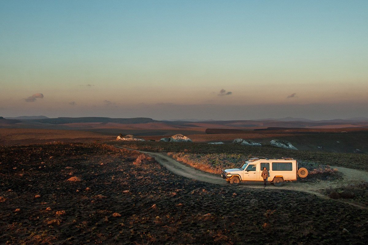 A safari vehicle parked on the burnt highland plateau near Chelinda Camp