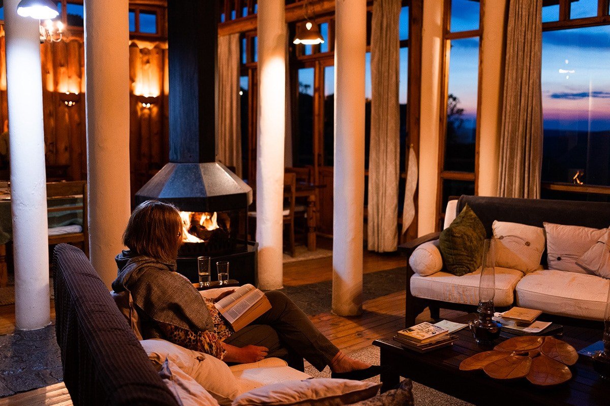 A guest reads by the fire in the lounge at Chelinda Lodge