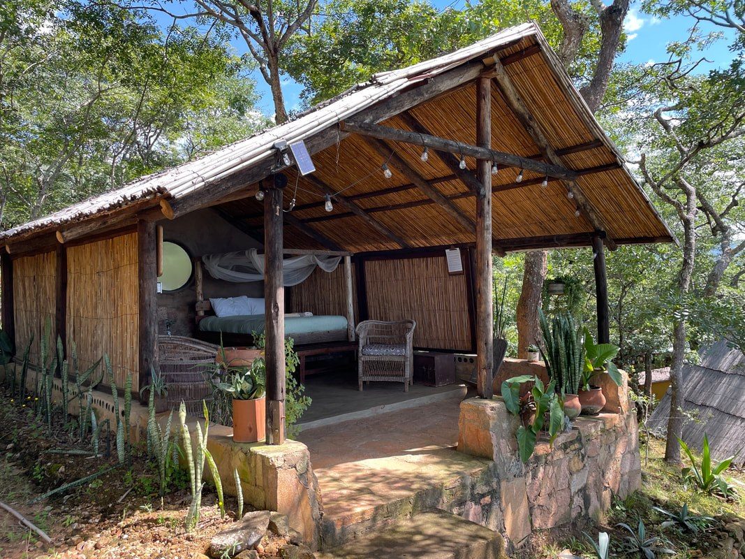 An open-air bamboo cottage with a mosquito-net bed sits among the trees at The Mushroom Farm
